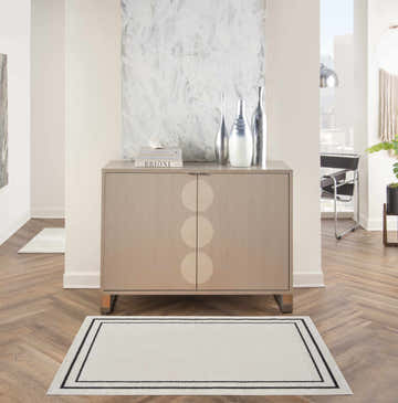 Living room scene with Nourison Essentials Ivory Black rug, wood floors, and modern cabinet.