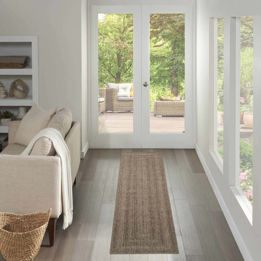 Hallway scene with a Nourison Tulum Brown Outdoor Area Rug runner leading to an outdoor patio.