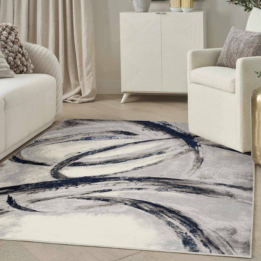 Living room scene with a Nourison Splash Grey Navy rug, white sofa and armchair, and modern white cabinet.