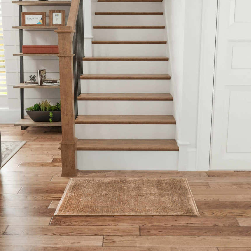 Entryway with wood floors and stairs featuring the Nourison Luxurious Taupe Vintage Indoor Area Rug.