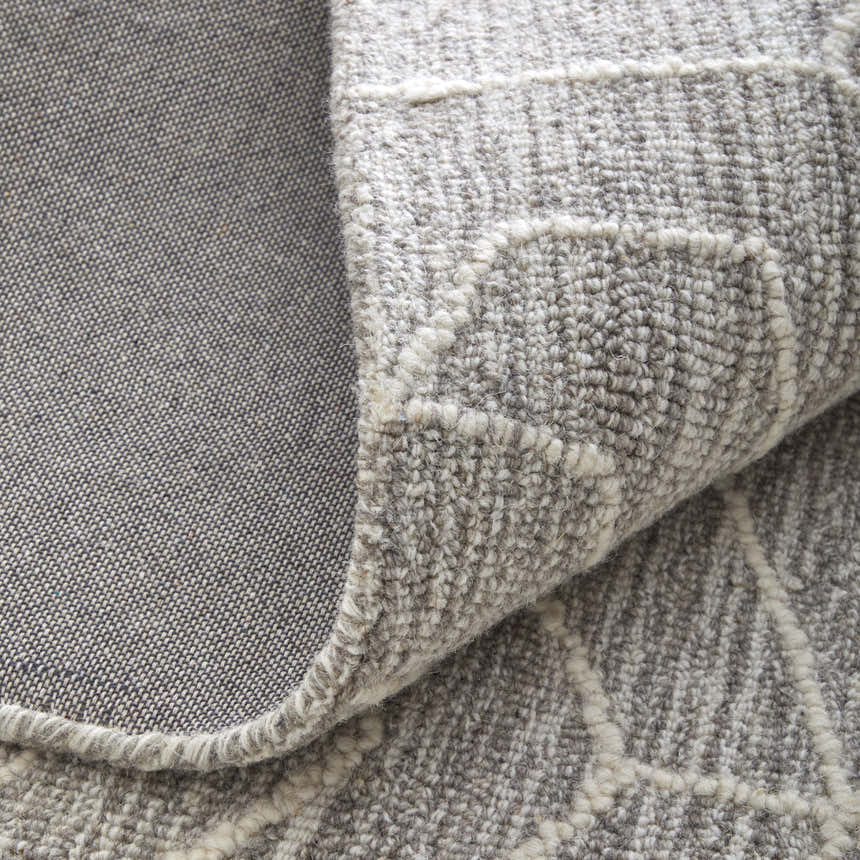 Close-up of the hand-tufted Feizy Emerson rug. Gray wool with ivory abstract pattern and cotton backing detail. Fold