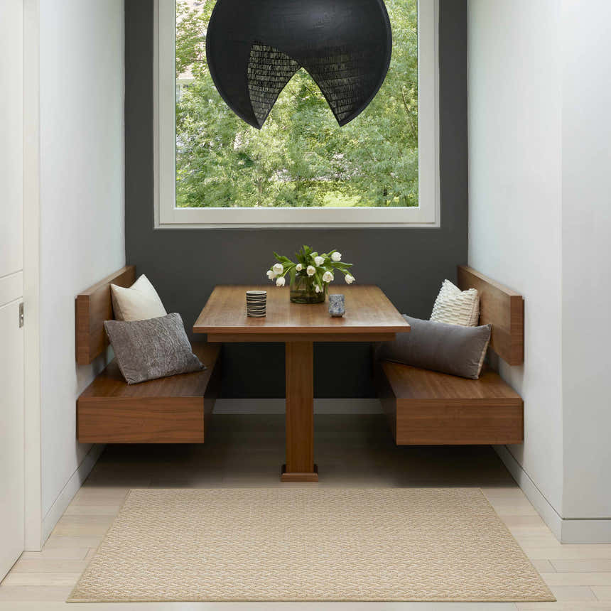 Breakfast nook with wood benches and a cream Nourison Tulum Outdoor Area Rug.
