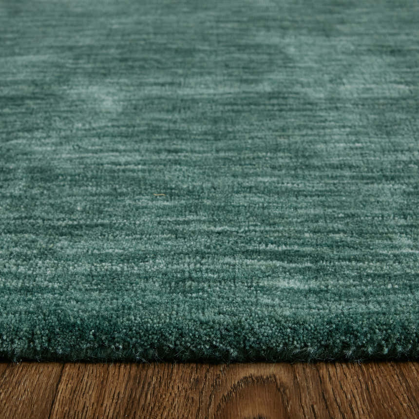 Close-up of the textured Feizy Luna Modern Solid green and white wool area rug on a wood floor. Pile