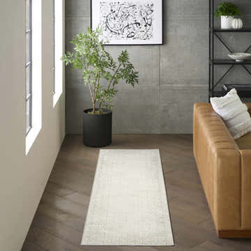 Modern living room with DKNY Grand Street Ivory rug, chestnut leather sofa, and black shelving.