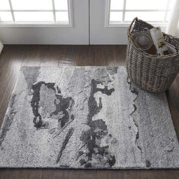Entryway with gray Nourison Divine Smoke Modern Indoor Area Rug, dark wood floors, white doors, and a woven basket.