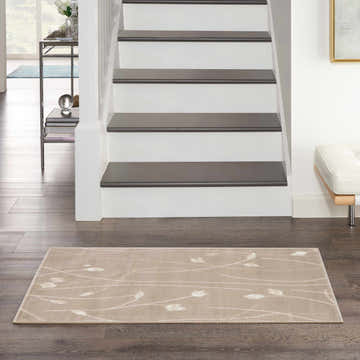 Entryway with stairs and a beige Nourison Grafix area rug with a subtle floral pattern on dark wood floors.