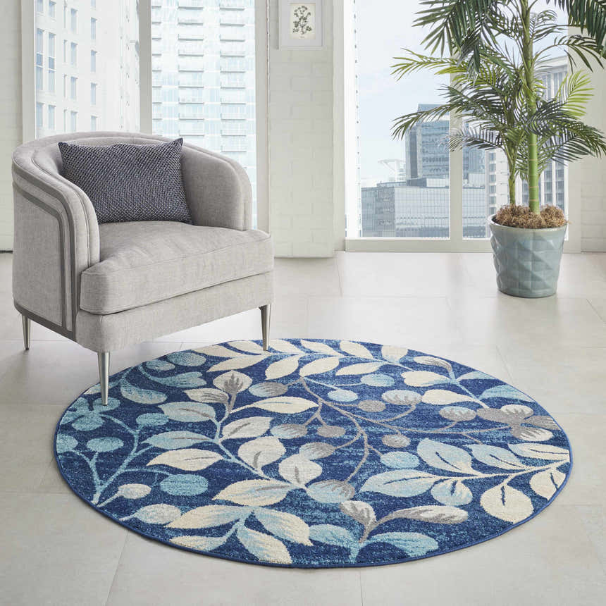 Bright room with gray chair and round Nourison Tranquil Navy rug featuring a blue and white leaf pattern.