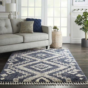 Living room with a gray sofa and Nourison Oslo Denim Blue Shag rug with geometric pattern and tassels.