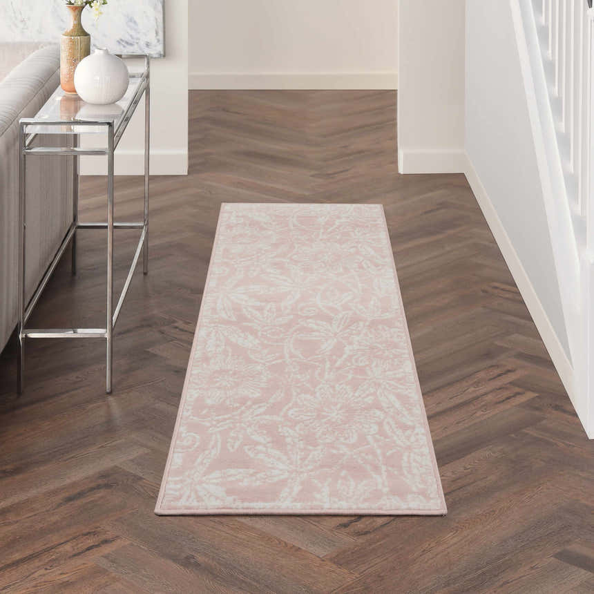 Hallway scene with a Nourison Whimsicle Pink Farmhouse runner rug on dark wood floors. Features a glass console table and white walls.