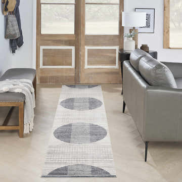 Entryway with gray bench, leather sofa, and Nourison Astra Ivory Blue runner rug with mid-century modern circle pattern.
