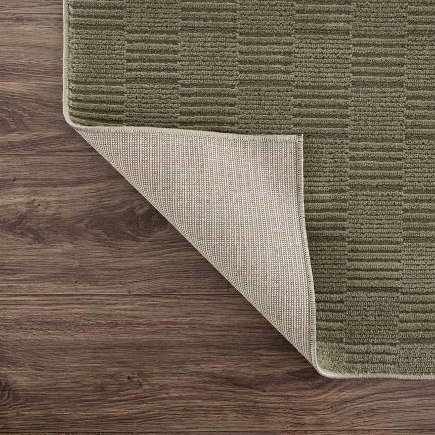 Close-up of Kazuma Green Washable Area Rug showing its textured, low-pile design and non-slip backing. Green and gray tones. Fold