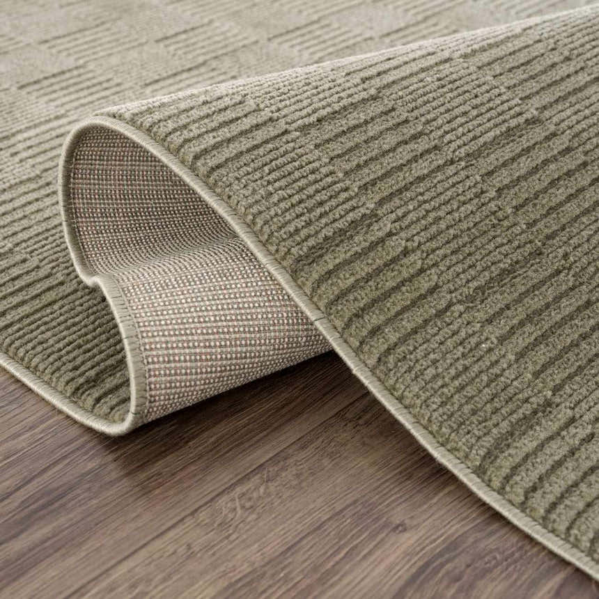 Close-up of the Kazuma Green Washable Area Rug showing its textured, linear design and durable backing on a wood floor. Fold