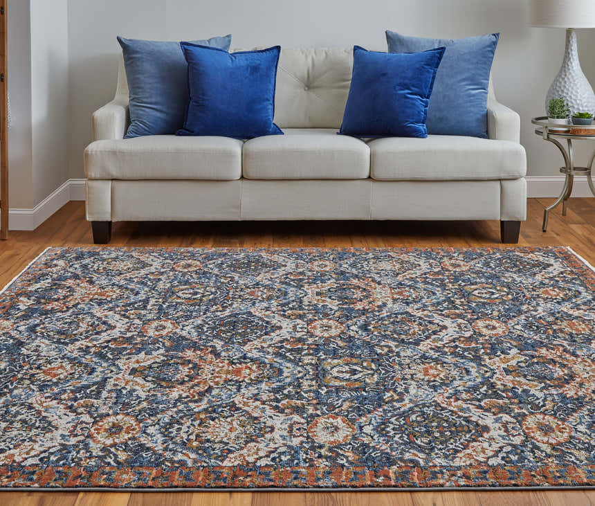Living room scene with Feizy Kaia rug in blue, orange, and ivory. The rug is styled with a cream sofa and blue pillows. Roomscene-Rectangle