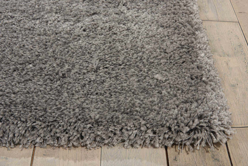 Close-up of the plush texture and silver gray color of the Nourison Yummy Shag rug on a wood floor.