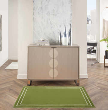 Entryway with a Nourison Essentials Green Ivory rug, wood floors, and a cabinet with silver vases.