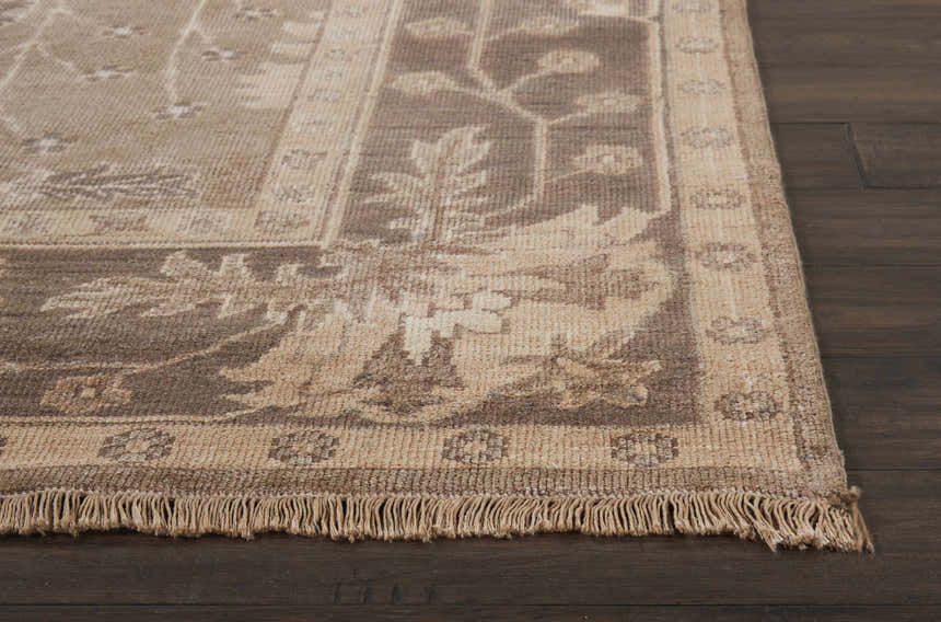 Close up of the Opal Gray Nourison Aldora rug showing vintage floral pattern and fringe detail on dark wood floor.