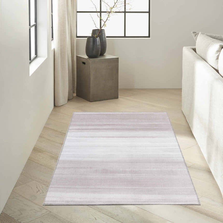 Minimalist living room with a Calvin Klein Launder Ivory rug, light wood floors, and a neutral sofa.