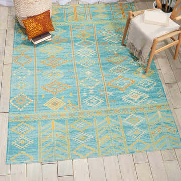 Styled room featuring Nourison Madera Sky Blue Tribal rug. Sky blue and gold geometric pattern on a wood floor.