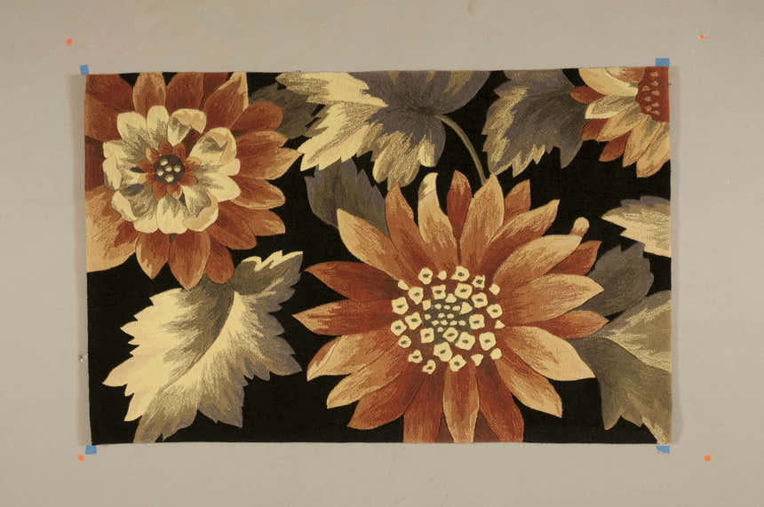 Close-up of the Nourison Contour Black Indoor Area Rug, featuring large floral blossoms in shades of rust, cream, and gray on a black ground.