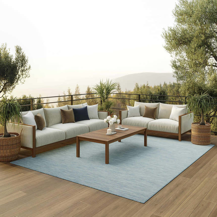 Outdoor patio scene with sofas and a Nourison Positano Aqua rug, offering a serene and stylish space.