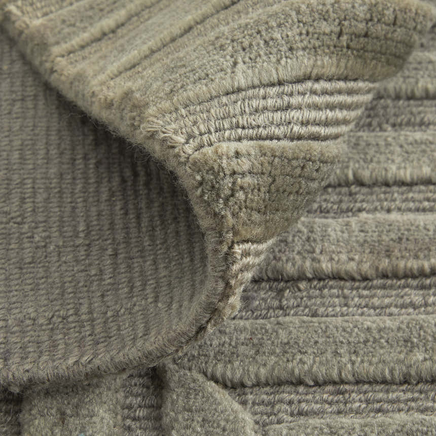 Close-up of the hand-knotted Feizy Channels rug. Modern geometric design in taupe, green, and blue wool. Soft, textured pile. Fold