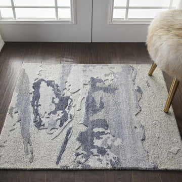 Entryway with a Nourison Divine Slate rug in taupe and gray, paired with a furry chair on dark wood floors.