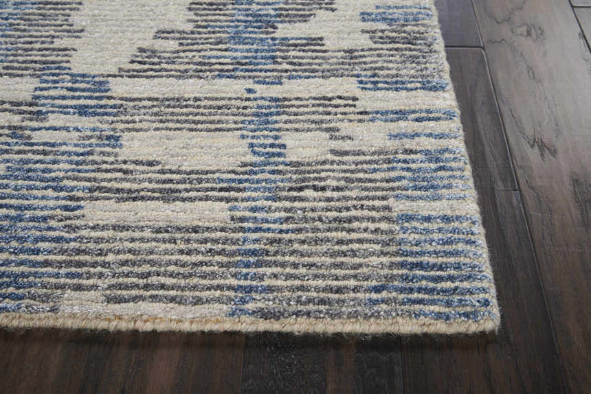 Close-up of Nourison Ellora Blue rug showing the light blue, gray, and ivory horizontal pattern and handmade texture.