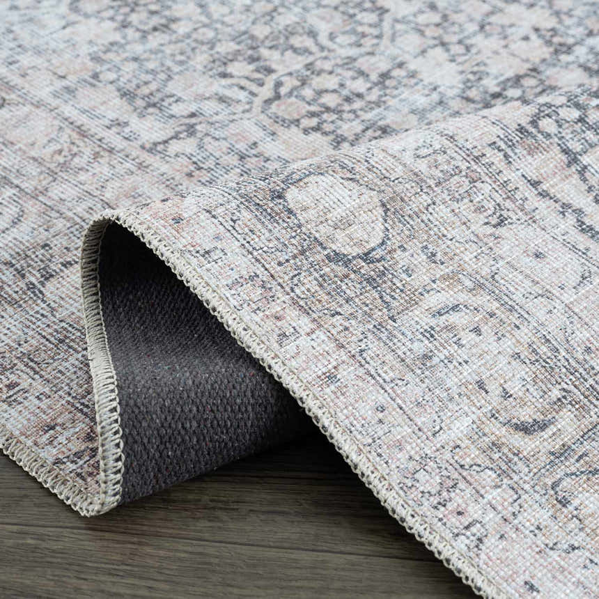 Close-up of the Hedda Boutique Washable Rug showing its vintage-style pattern, gray, brown, and nutmeg colors, and machine-woven texture. Fold