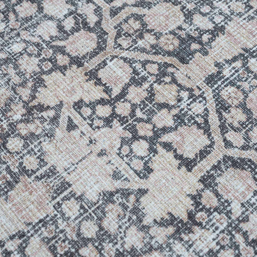 Close-up of the Hedda Boutique Washable Rug. Features a traditional, vintage pattern in dark gray, nutmeg, and light gray hues. Texture