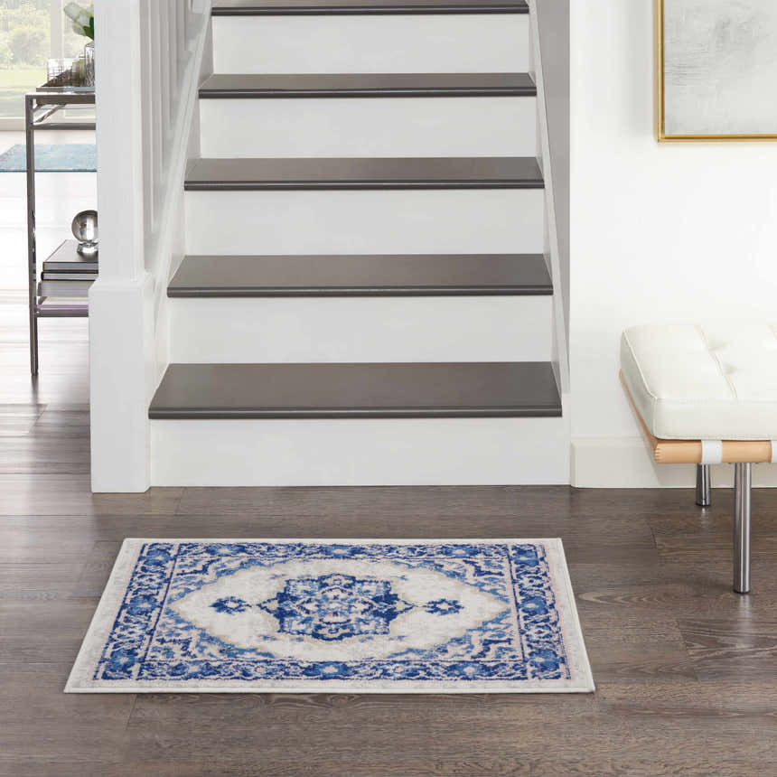 Entryway with Nourison Whimsicle Ivory Blue Farmhouse Indoor Area Rug, wood floors, white stairs, and modern bench.