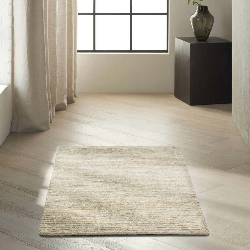 Minimalist room scene with a Calvin Klein Mesa Gypsum rug on light wood floors and neutral curtains.