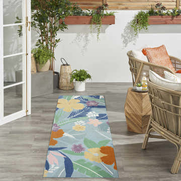Tropical patio scene with rattan chairs and blue multicolor Nourison Suncoast area rug runner.
