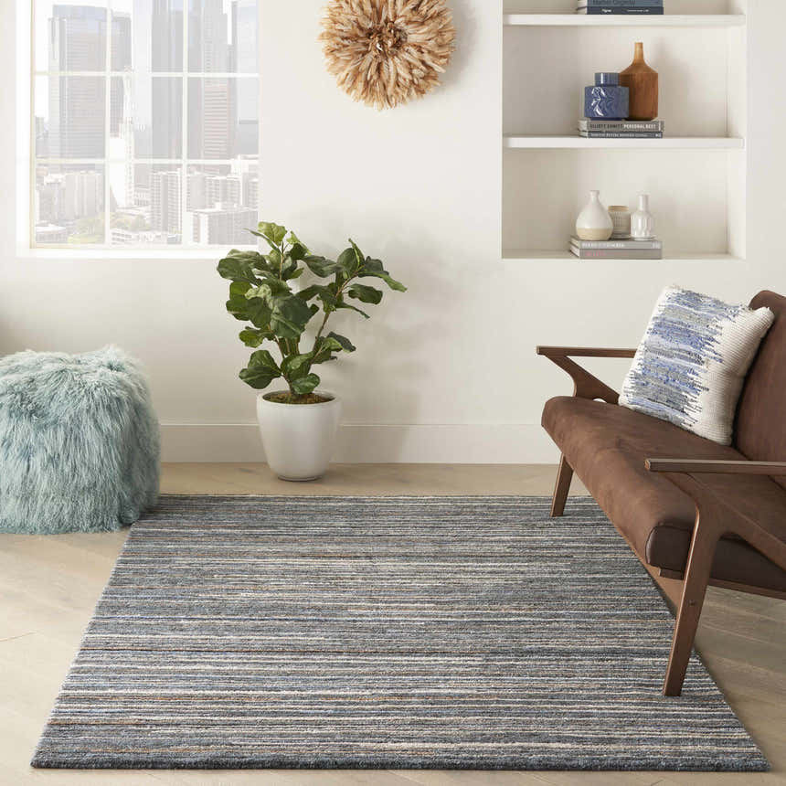 Modern living room with a Nourison Plateau Blue rug, brown chair, and city view.