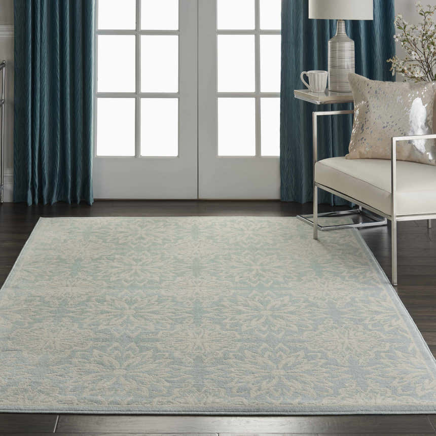 Living room scene with Nourison Jubilant Ivory Green rug, white chair, blue curtains, and dark wood floors. Farmhouse style.