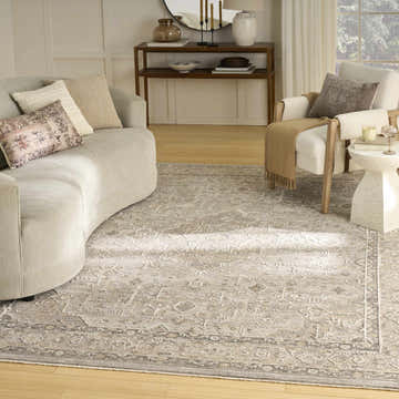 Living room scene with a Nourison Retreat Grey Vintage Indoor Area Rug, curved sofa, and neutral decor.