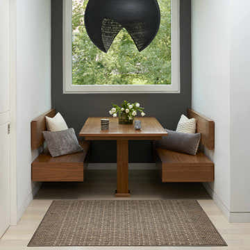 Breakfast nook with wood benches and a Nourison Tulum Brown Outdoor Area Rug on light wood floors.