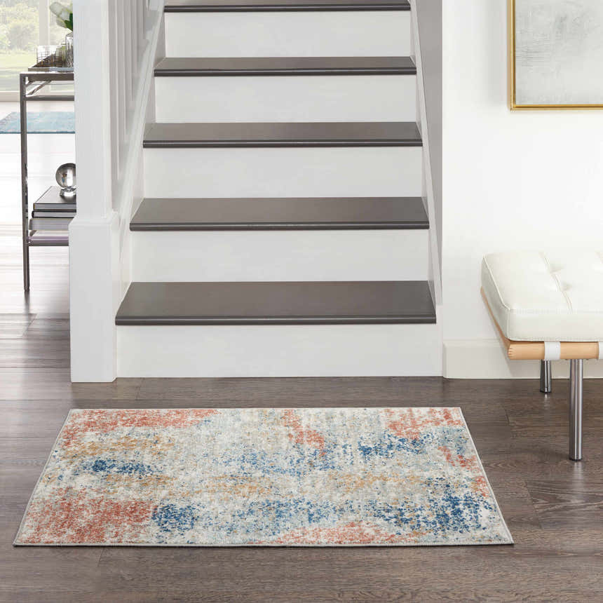 Entryway with Nourison Quarry Ivory Multicolor Rug, stairs, dark wood floor, and white bench.