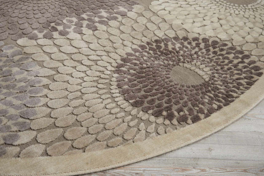 Close up of the grey Nourison Graphic Illusions rug. Features a circular mid-century modern design in shades of taupe and brown.
