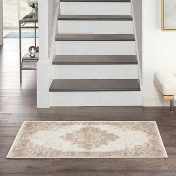 Entryway scene with a Nourison Grafix Ivory Beige Vintage rug on dark wood floors, stairs, and a white bench.