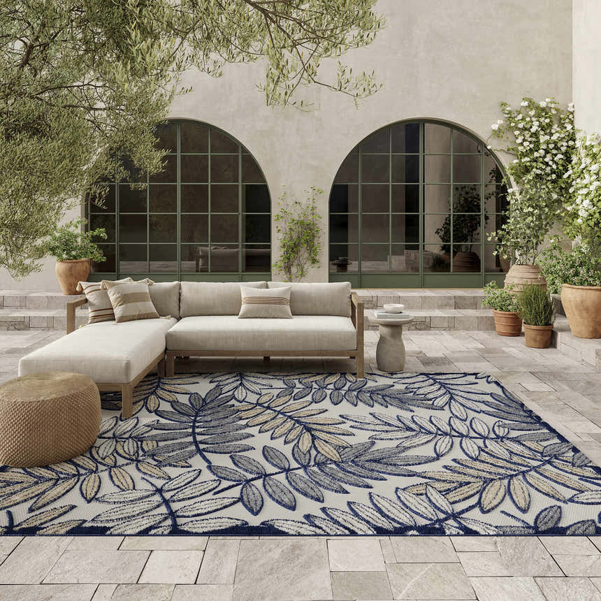 Outdoor patio scene with a beige sectional sofa on a Nourison Aloha Ivory Navy Tropical Area Rug.