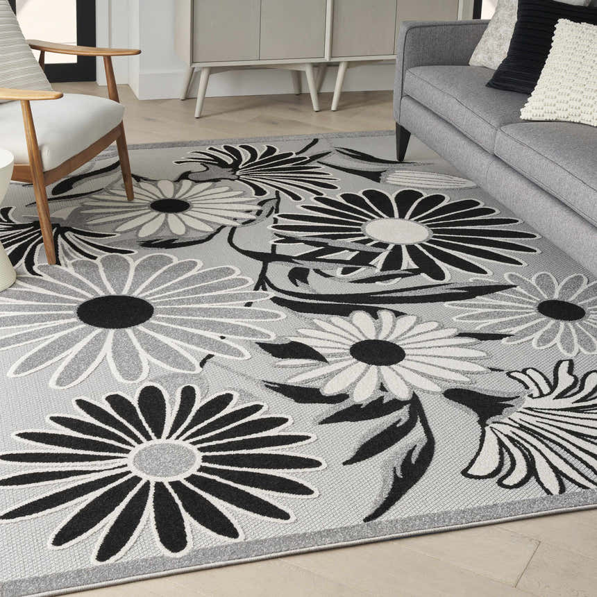 Living room scene with a Nourison Aloha Black White Outdoor Area Rug featuring a floral pattern.