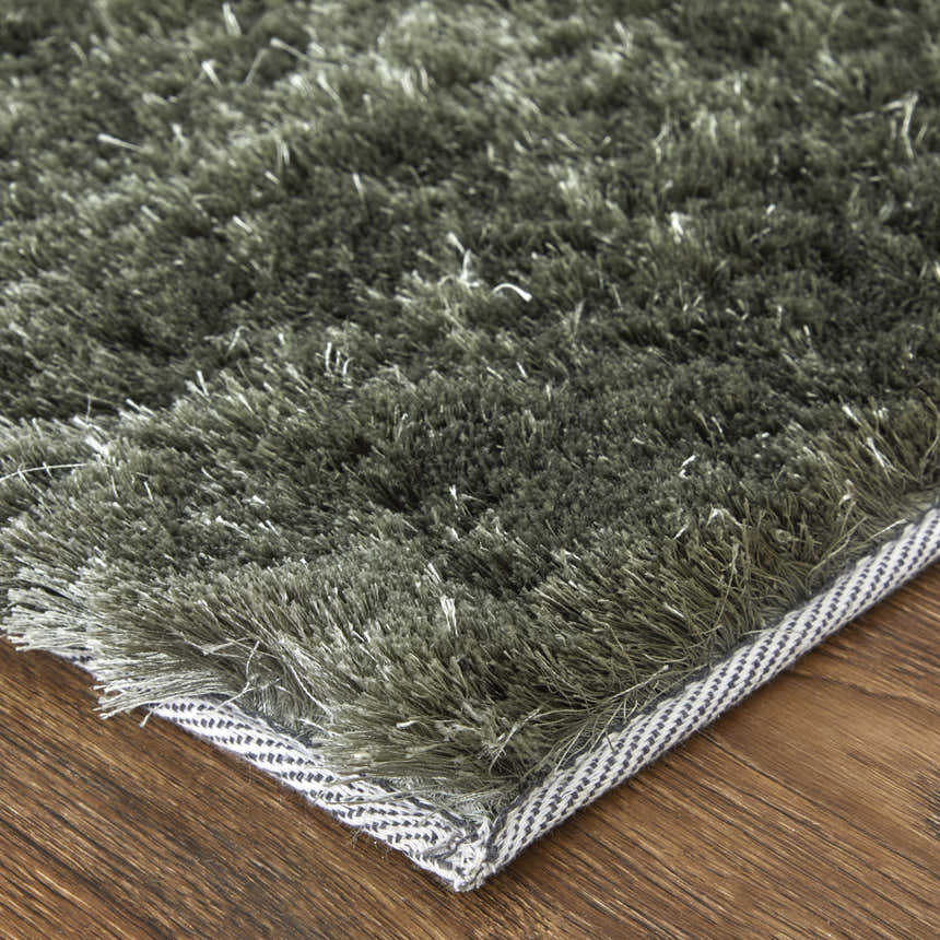 Close up of the Feizy Indochine Modern Solid Green Area Rug showing its plush texture and bound edge on wood floor. Swatch