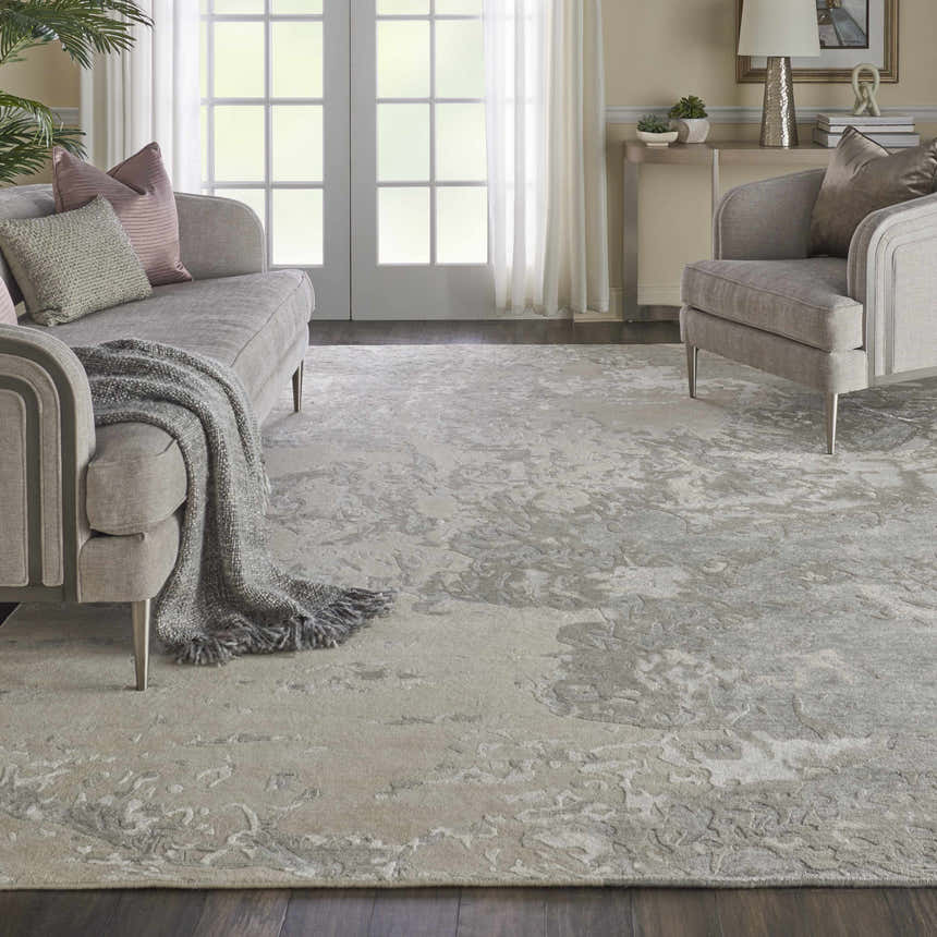 Living room scene with the Nourison Silk Shadows Sand modern rug, gray sofa, and natural light.