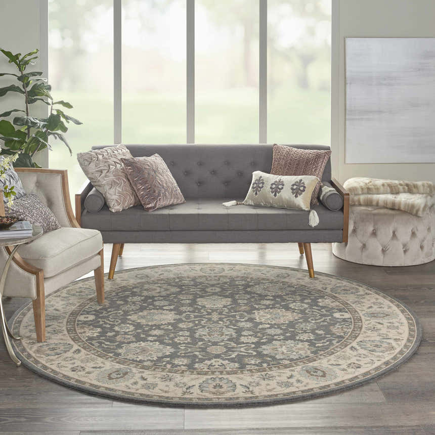 Living room scene with a round Nourison Living Treasures Grey Ivory Farmhouse rug, sofa, chair, and ottoman.