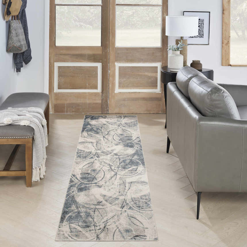 Entryway with gray leather bench and sofa featuring Nourison Astra Silver Blue area rug.