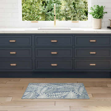 Light blue Nourison Aloha rug in a modern kitchen with navy cabinets and wood floors.