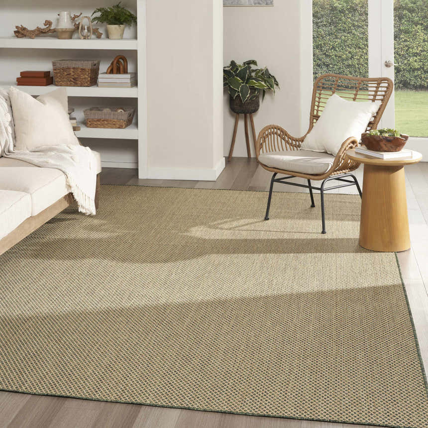 Living room scene with a Nourison Courtyard Green Modern Area Rug, neutral sofa, wicker chair, and natural light.