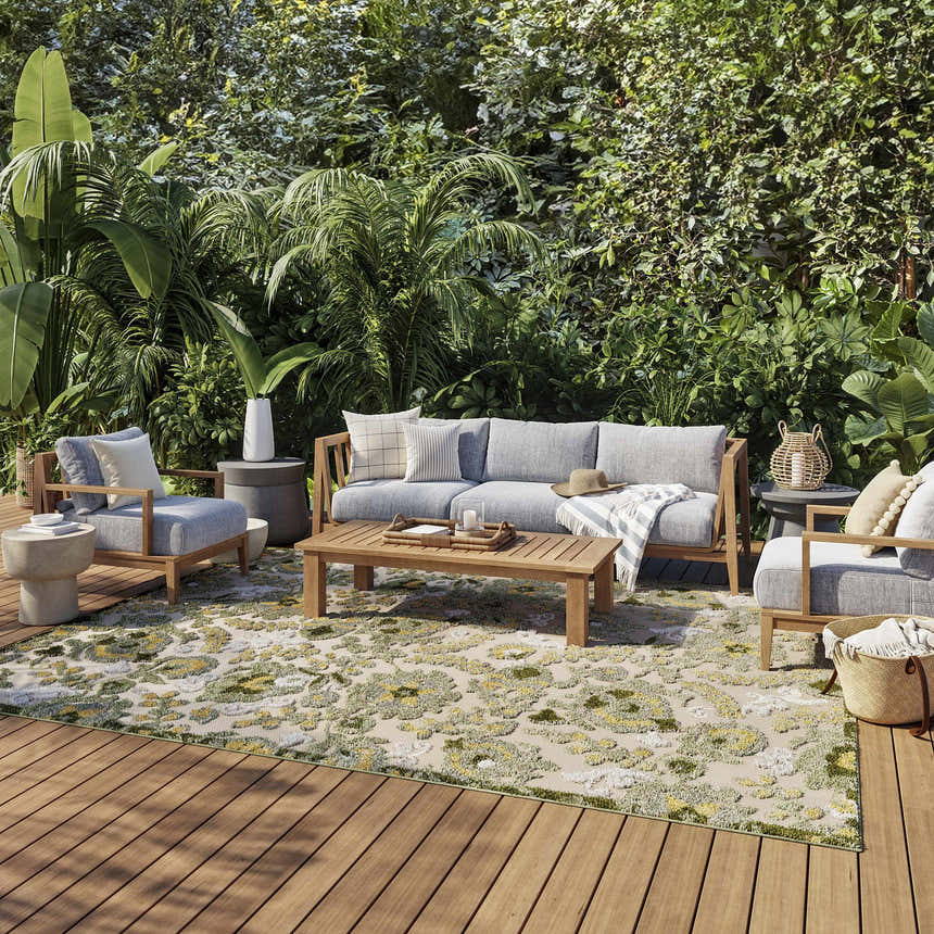 Outdoor patio scene with a Nourison Aloha Ivory Green rug, gray furniture, and lush greenery.