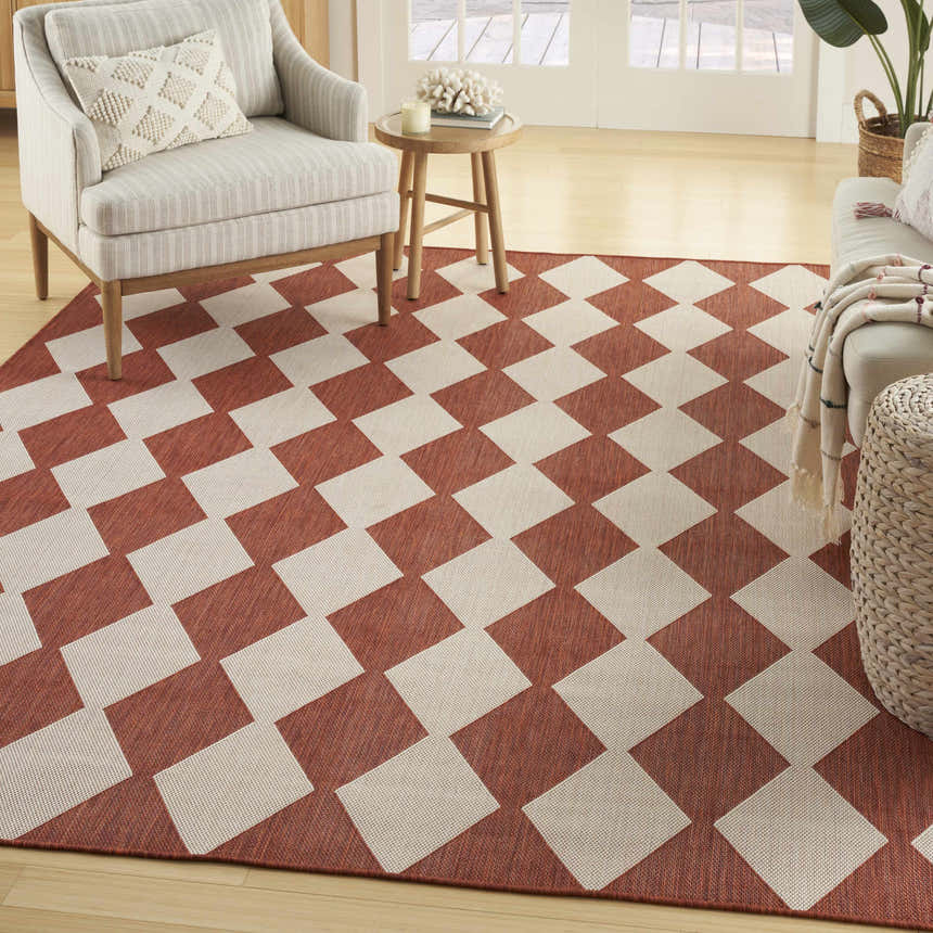 Living room scene with a Nourison Positano Terracotta rug, striped armchair, wood side table, and neutral sofa.