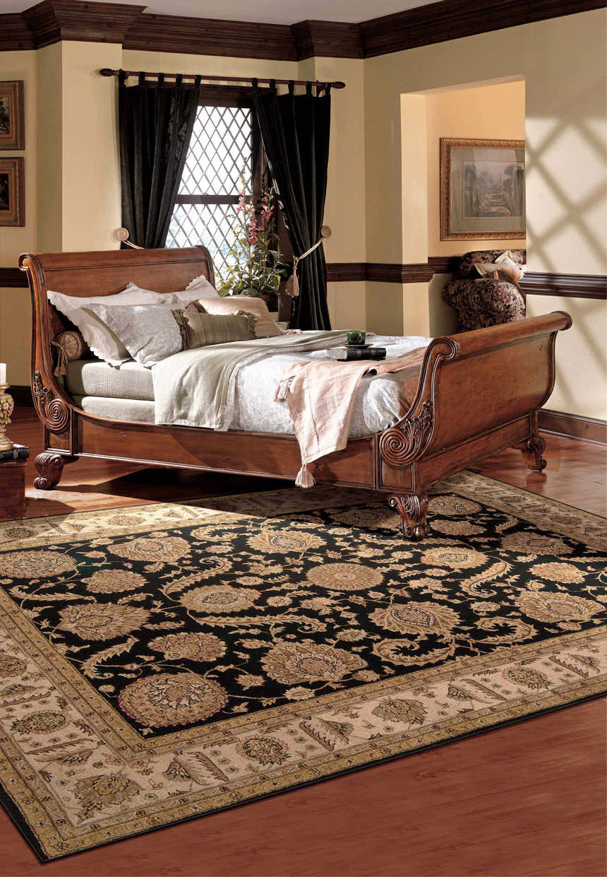 Bedroom scene with a Nourison Heritage Hall Black Persian rug, wood sleigh bed, and dark curtains.